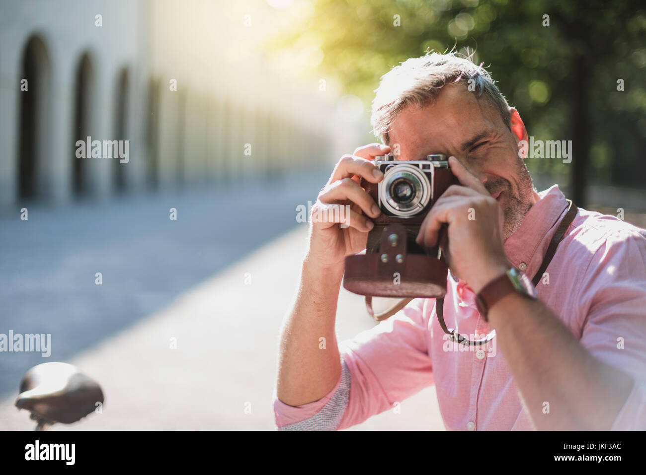 Man taking pictures with an old-fashioned camera in a park Stock Photo