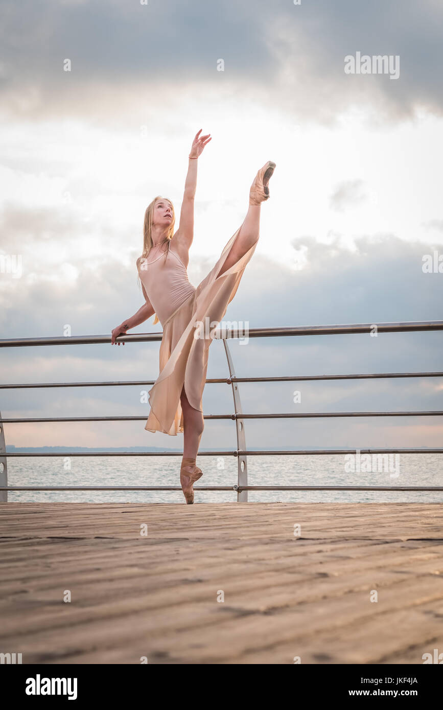 Dancing ballerina in beige silk dress and pointe on embankment above ocean  or sea beach at sunrise. Young beautiful blonde woman with long hair practi  Stock Photo - Alamy