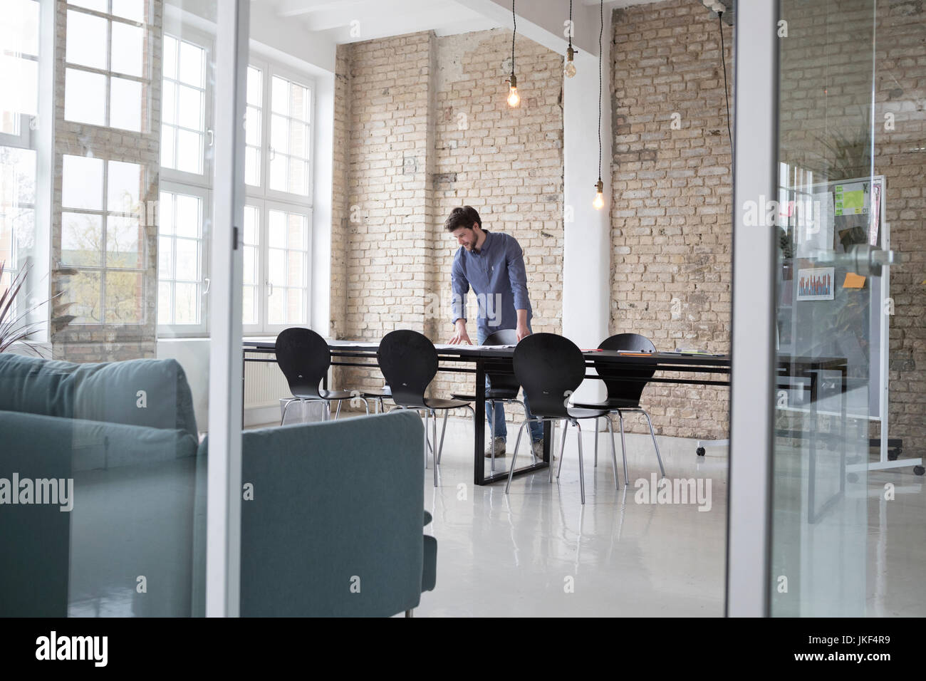 Young entrepreneur standing in his office, looking at plans Stock Photo