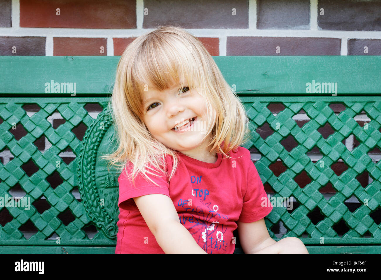 Portrait of smiling little girl on garden bench Stock Photo - Alamy