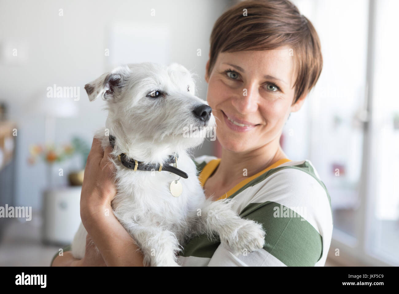 Portrait of smiling woman holding dog on her amrs Stock Photo