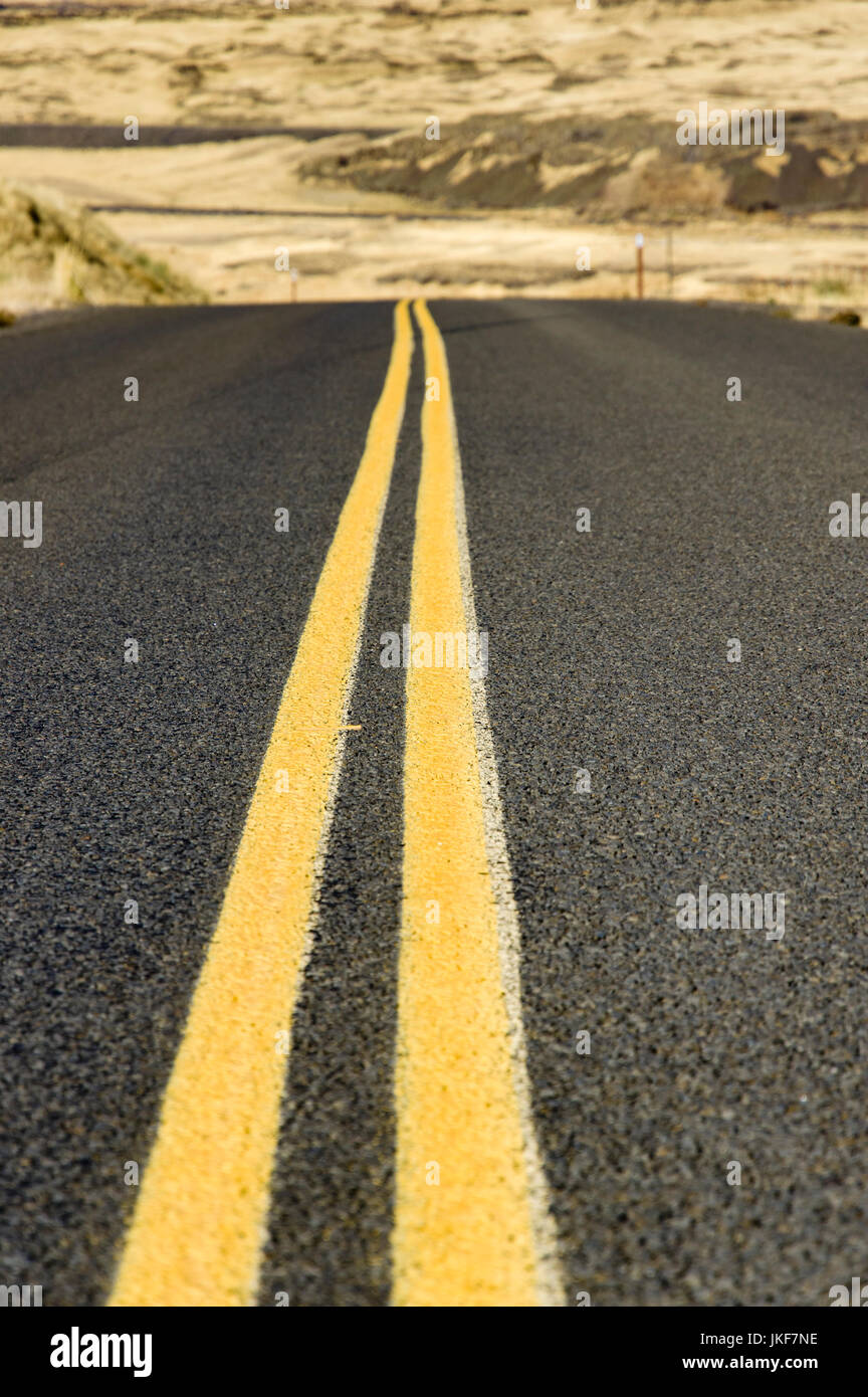 Double yellow lines on paved road in rural desert area Stock Photo