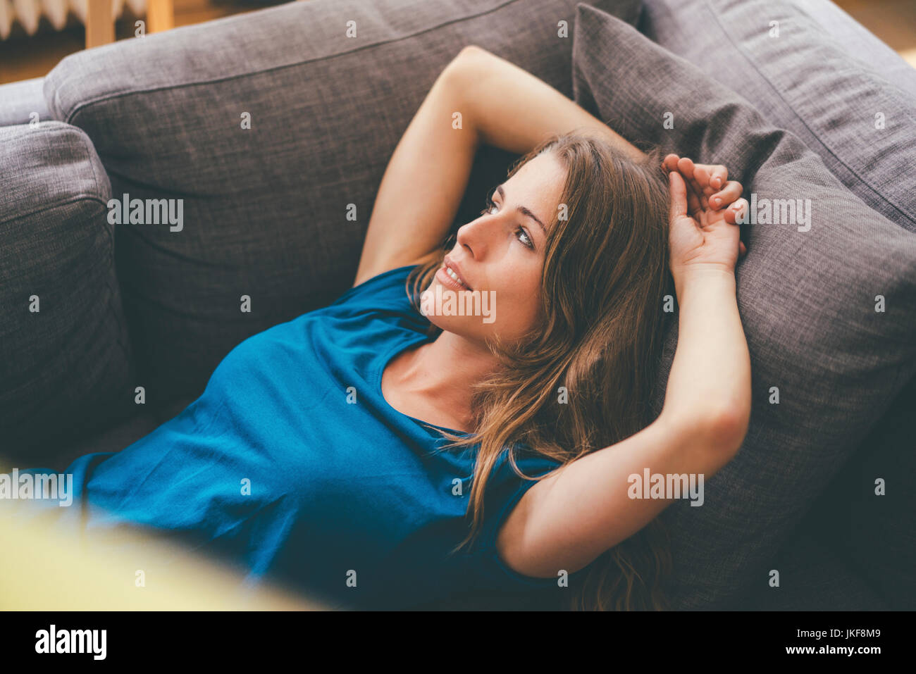 Relaxed young woman lying on couch at home Stock Photo - Alamy