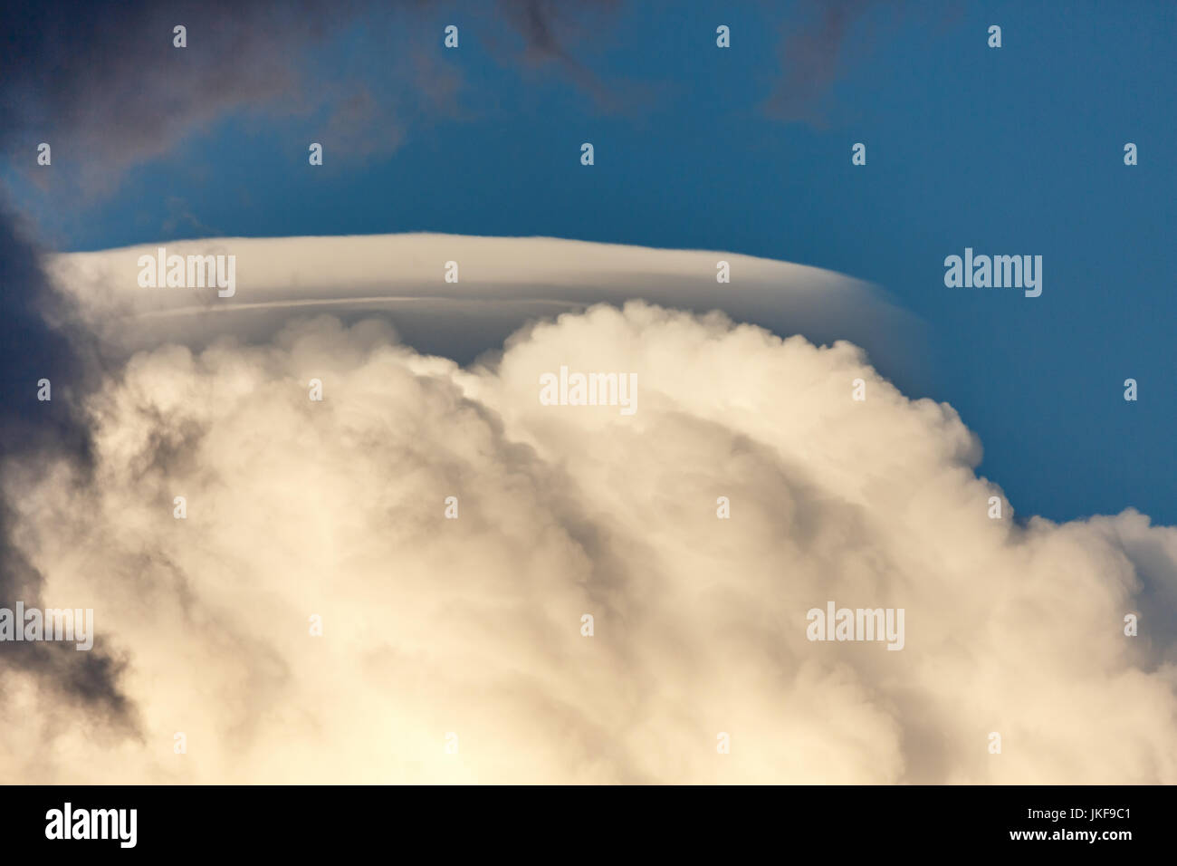 Rare Lenticular cloud (Altocumulus lenticularis) on top of a cumulus cloud infront of a blue sky in Wisconsin on a warm day in July Stock Photo