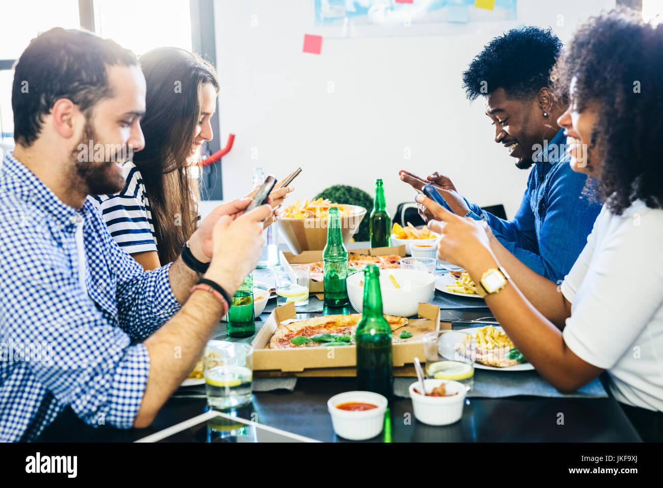 Friends using cell phones at dining table Stock Photo - Alamy