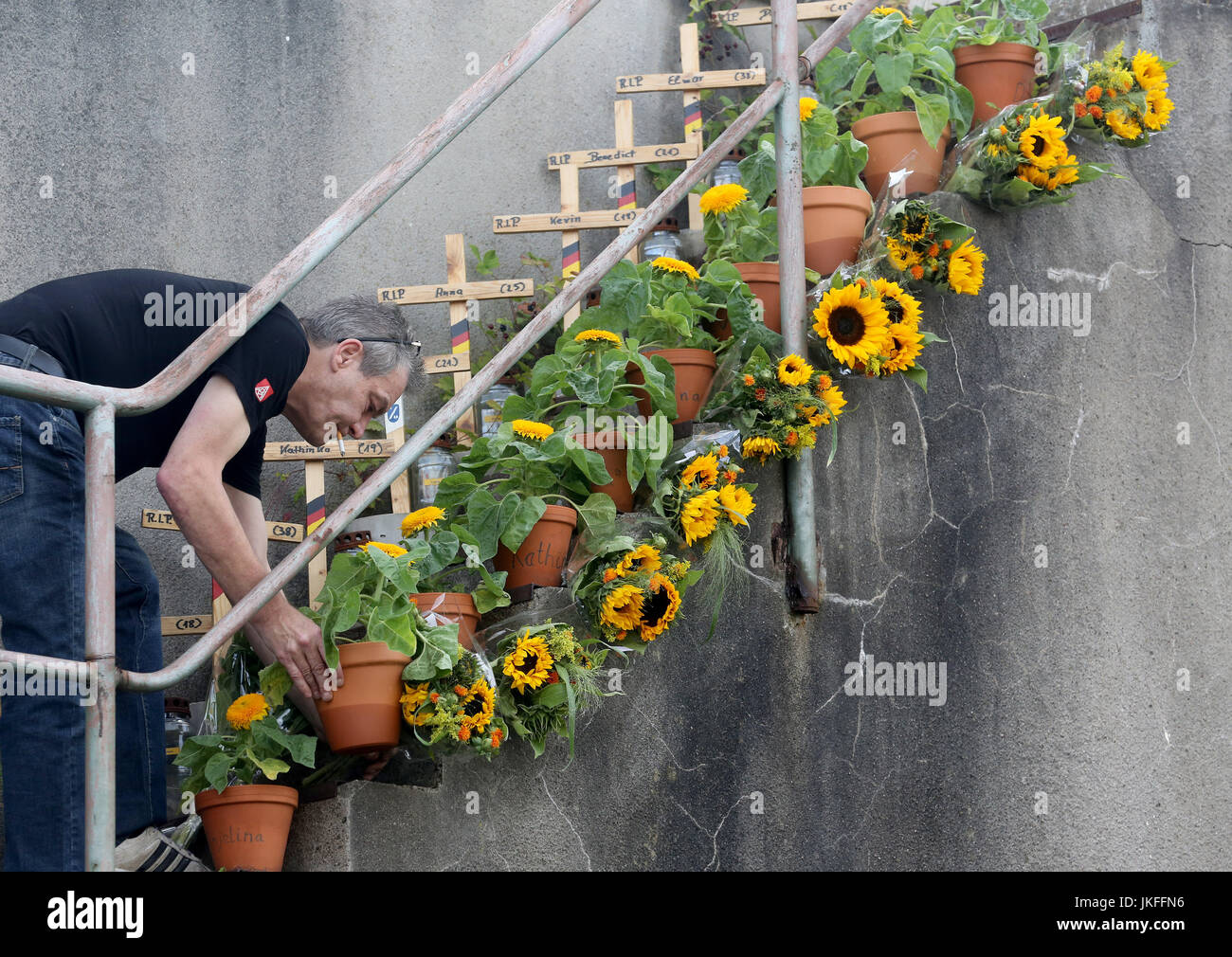 Duisburg, Germany. 23rd July, 2017. Fresh flowers being laid by a man during the 'Night of the thousand lights' in Duisburg, Germany, 23 July 2017. 21 people lost their lives here 7 years ago during the Loveparade. Photo: Roland Weihrauch/dpa/Alamy Live News Stock Photo