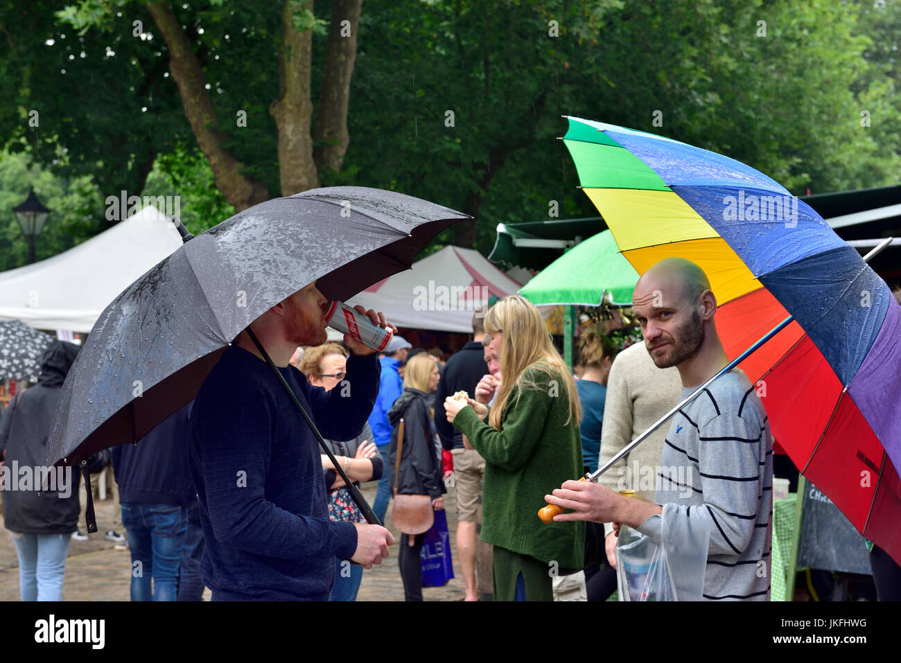 Bristol, UK. 23rd July, 2017. Rather mixed starting with heavy rain before the festival opened at 12:00 which then cleared to mixed sunshine and cloud. By 16:00 the forecasts were correct and a downpour commenced easing off at the official closing time for the festival. These two men came prepared with large umbrellas. © Charles Stirling/Alamy Live News. Credit: Charles Stirling/Alamy Live News Stock Photo