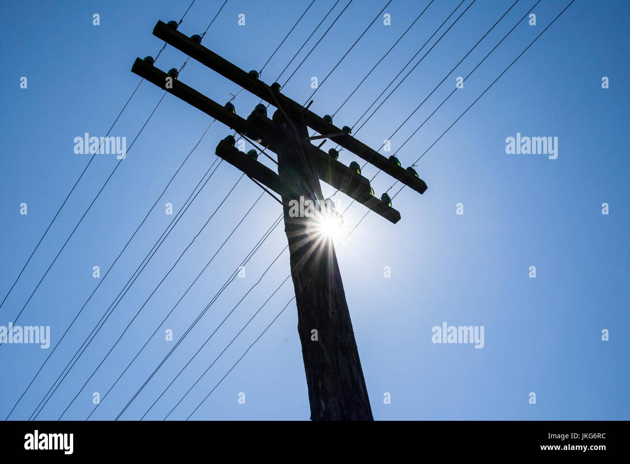 electric trellis with blue sky and sun in the background Stock Photo