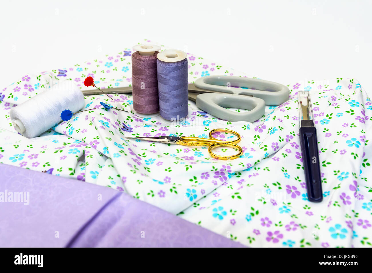 A selection of Sewing Accessories, including Scissors, Cotton, with Plain and Pattern Fabric displayed on white background. Stock Photo