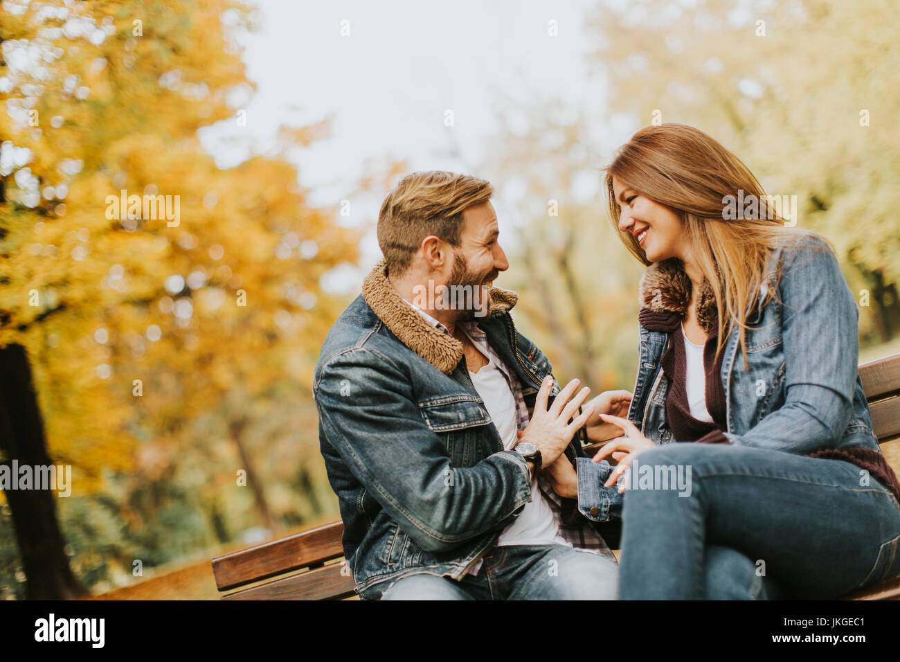 Young loving couple sitting on the bench in the autumn park Stock Photo ...
