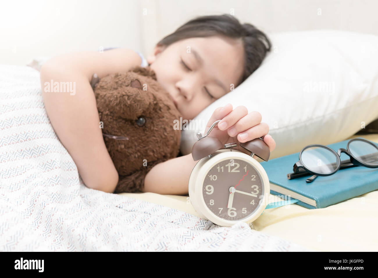 cute little hand girl reaching to turn off alarm clock on the bed in the morning Stock Photo Alamy