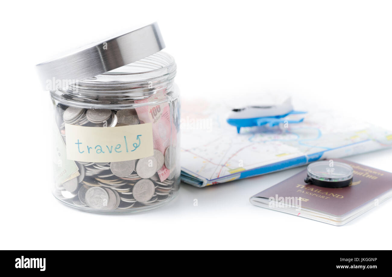 Travel budget concept. travel money savings in a glass jar with compass, passport and aircraft toy on world map isolated on white background Stock Photo