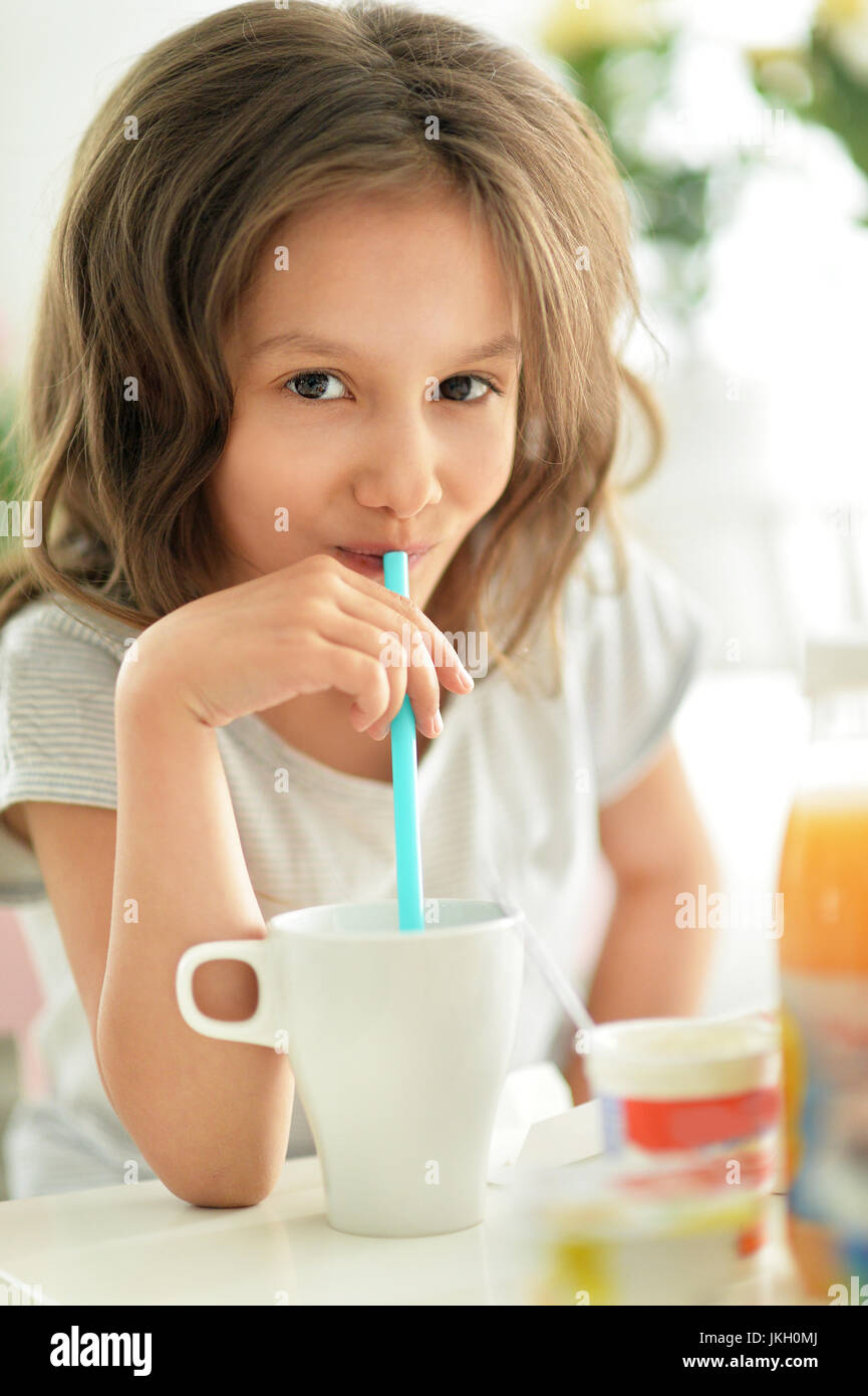 Cute little girl with cup drinking on the table Stock Photo Alamy