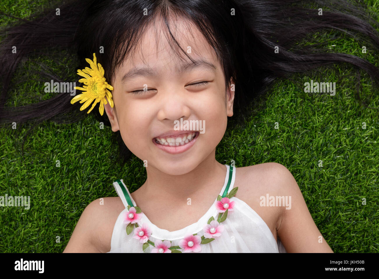 Asian Chinese Little Girl Lying On The Grass With Flower At