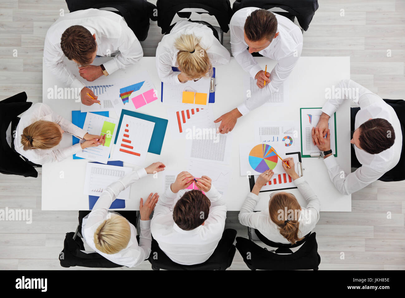 Business people work with statistics documents with tables and diagrams sitting around the table Stock Photo