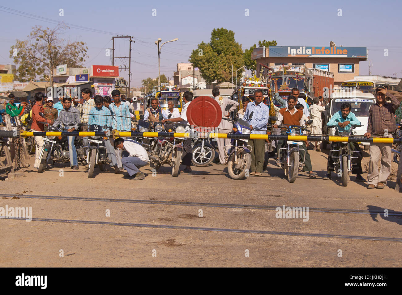 Crowd of vehicles fill the road waiting for the barriers to rise at a level crossing in Nagaur, Rajasthan, India. Stock Photo