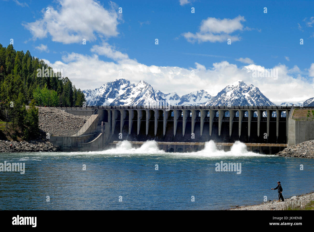 A boy fishes while water releases from Jackson Lake Dam on Jackson Lake