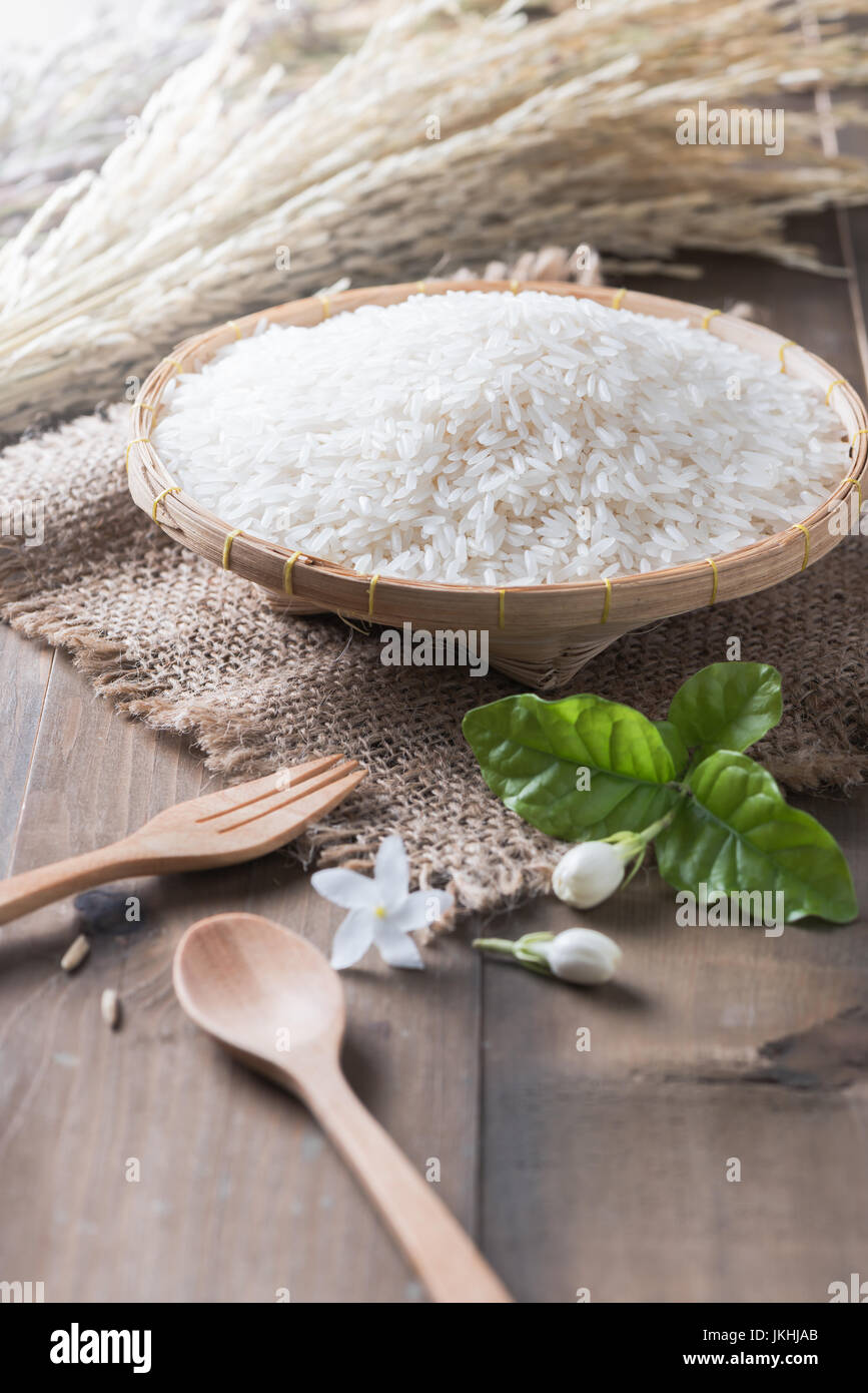 Thai jasmine rice, uncooked rice on bamboo basket with spoon and wood