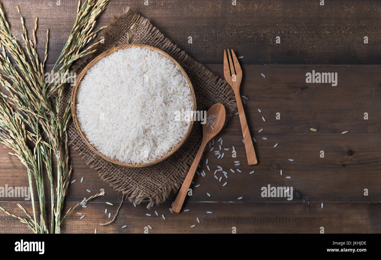 Thai jasmine rice, uncooked rice on wood background with spoon and wood