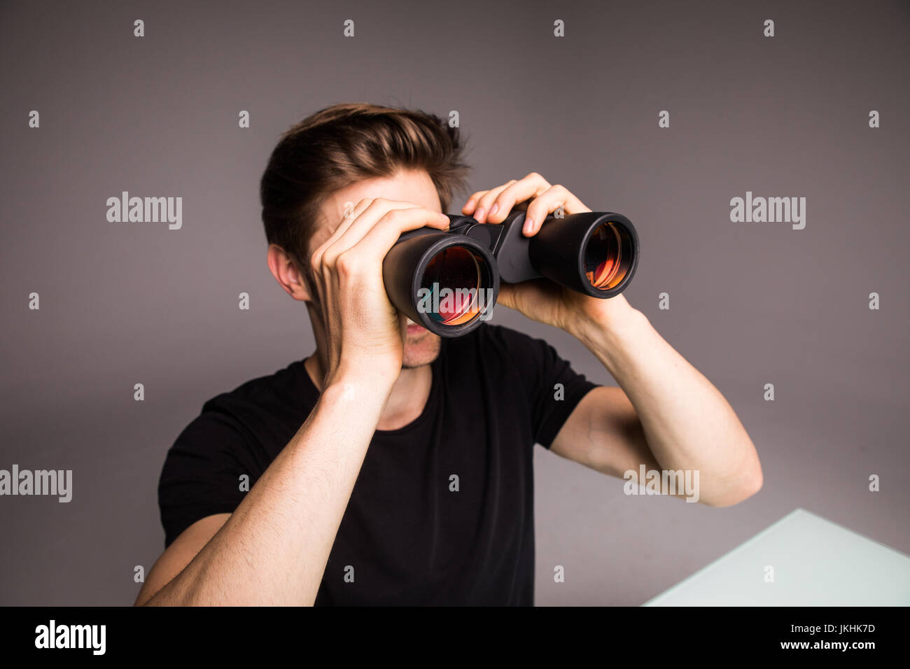Young handsome man searching with binoculars near laptop at office work  place Stock Photo - Alamy