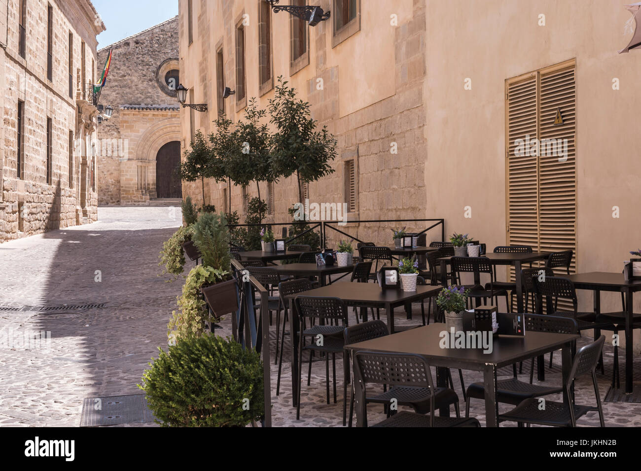 Terrace bar with tables and chairs are empty, near the church romanica of the Holy Cross, Baeza, Andalusia, Spain Stock Photo