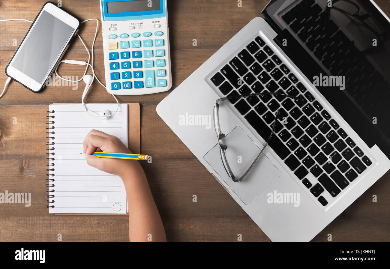 Office desk table with laptop, calculator, smartphone, pencil and