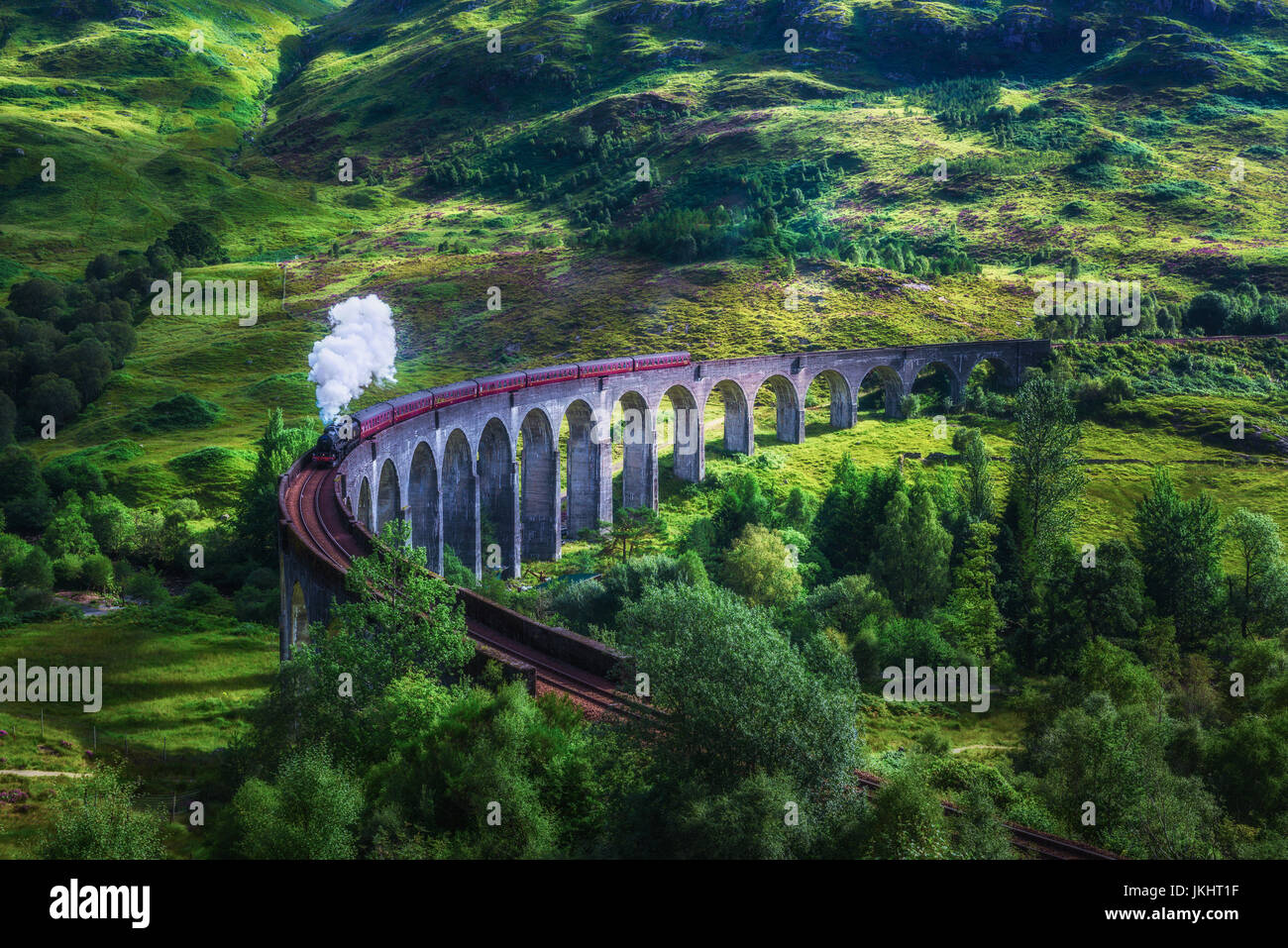 Glenfinnan Railway Viaduct in Scotland with the Jacobite steam train passing over. Artistic vintage style processing. Stock Photo