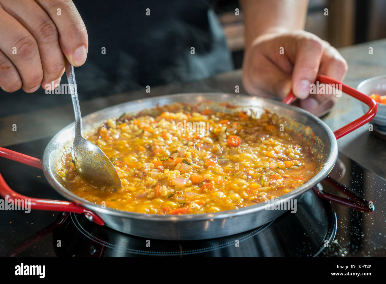 Chef is cooking paella with spoon, close up Stock Photo