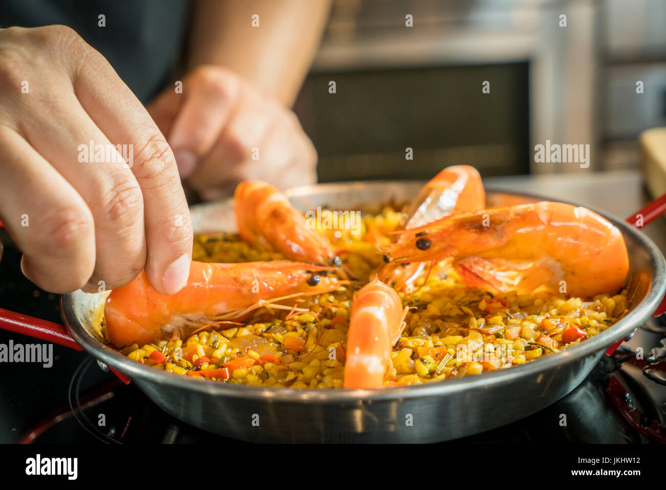 Chef is adding seafood to paella, close up Stock Photo