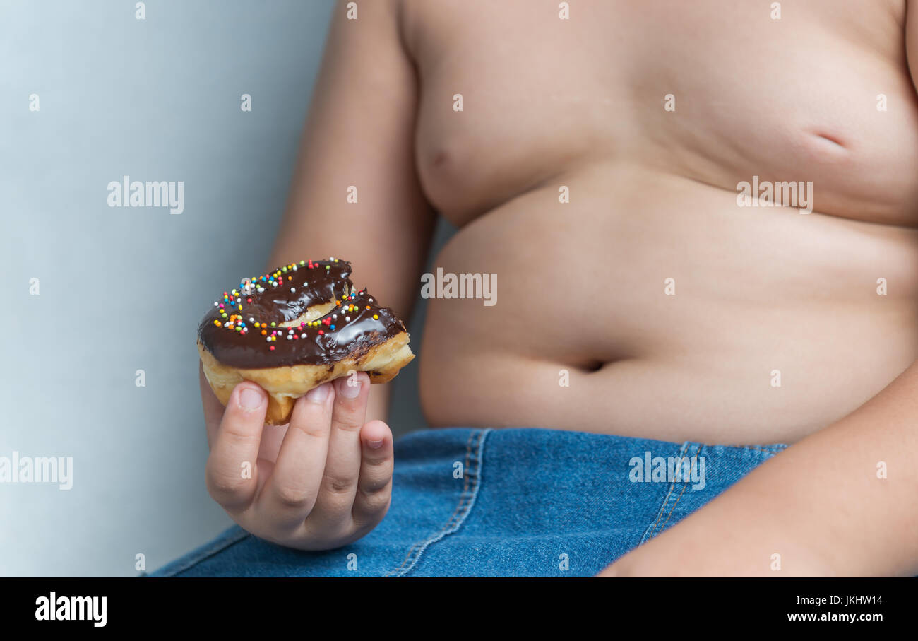 donut in obese fat boy, junk food can cause obesity. Stock Photo