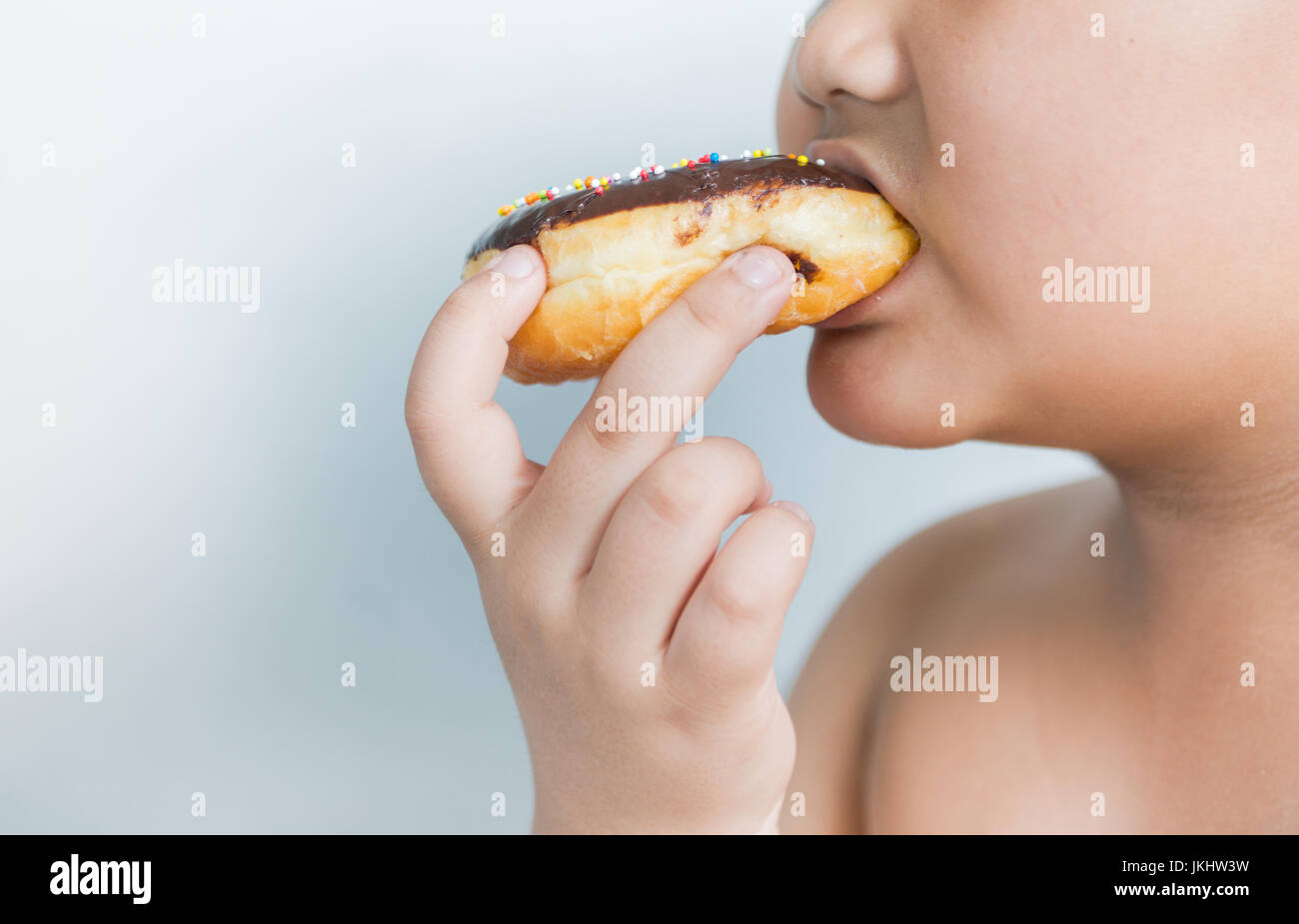 obese fat boy eat donut on gray background Stock Photo