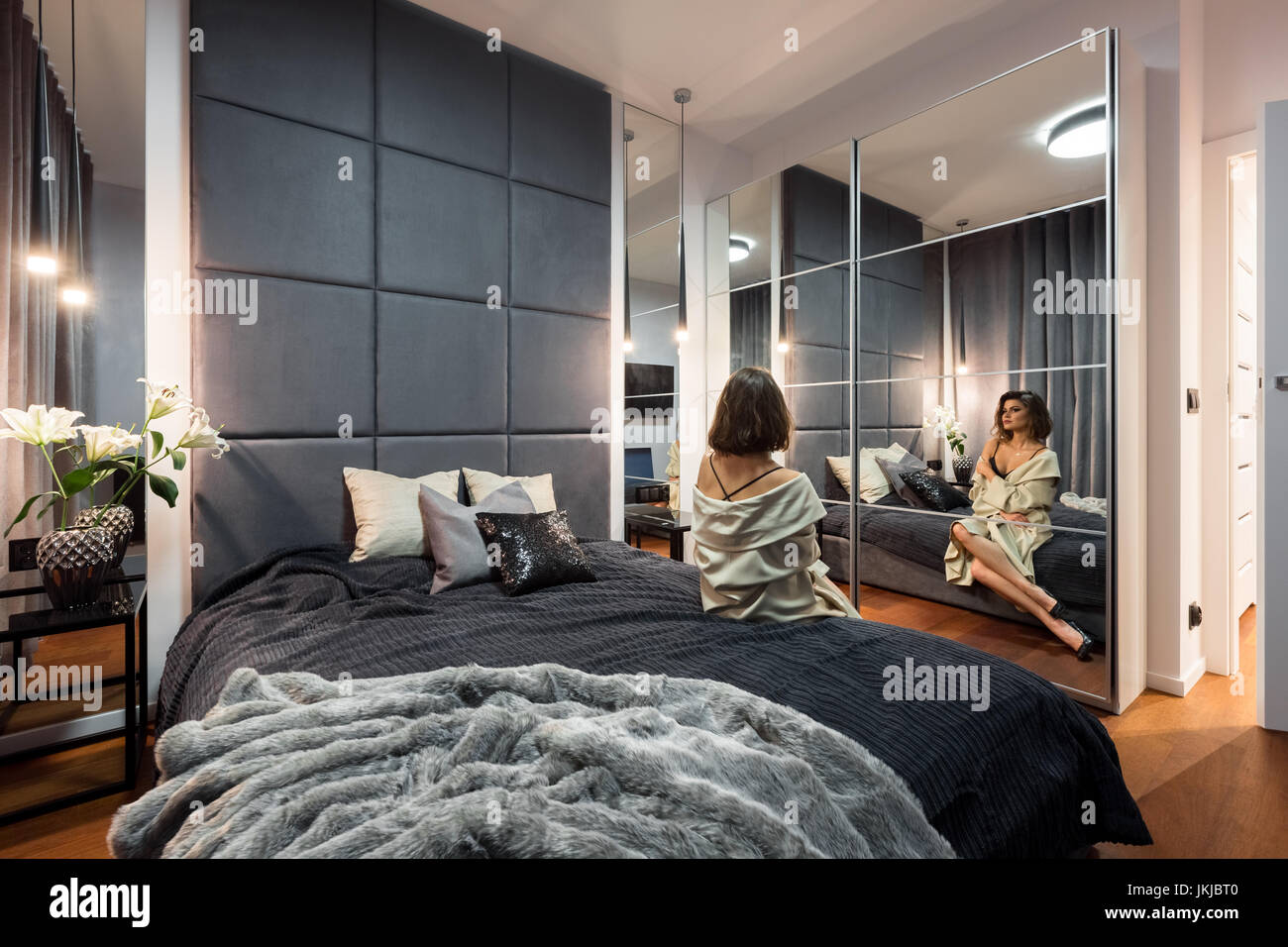 Beautiful Woman Sitting On Bed In Modern Bedroom With Double Bed