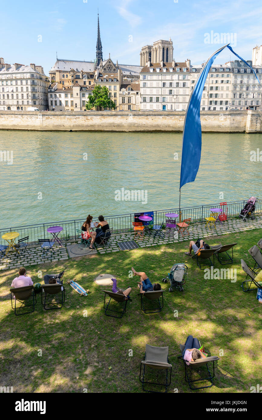 Paris, France - July 18, 2017: During summer event 'Paris Plage' on the wharf of the river Seine, people resting in the shade on lounge chairs, opposi Stock Photo