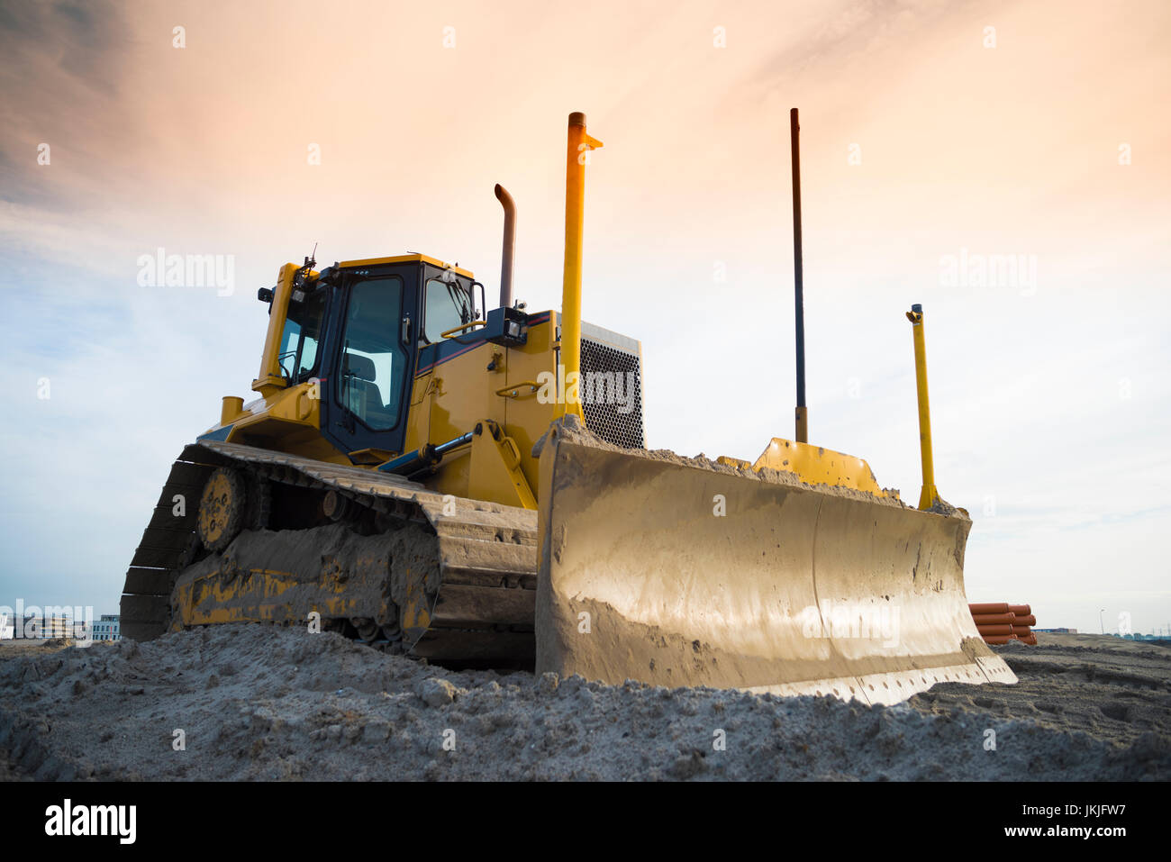 yellow excavator on a construction site in front of an orange sky Stock ...