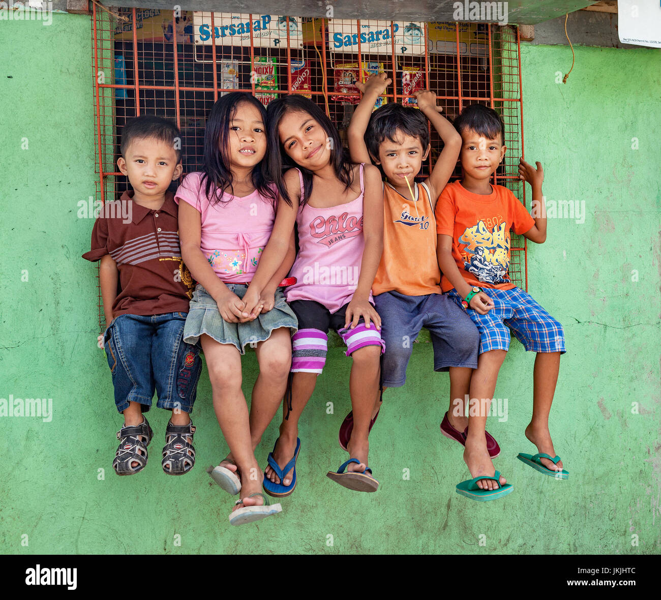 Five young Filipino children sit on a window ledge for a group portrait in Cadiz City, Negros Occidental Island, Philippines. Stock Photo
