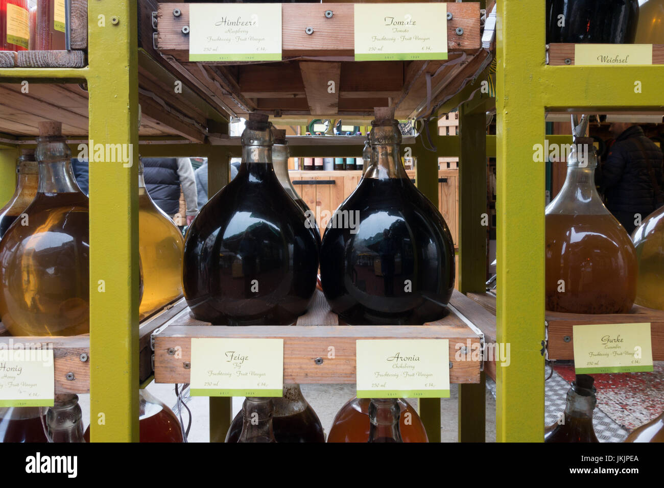 Several different types of fruit vinegar in large glass container jugs on display for sale stacked on shelves in street market Stock Photo