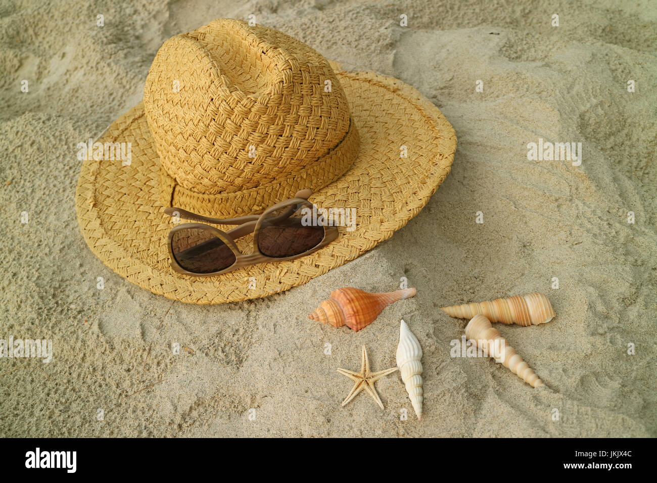 Light brown straw hat and brown sunglasses on the sandy beach with many ...