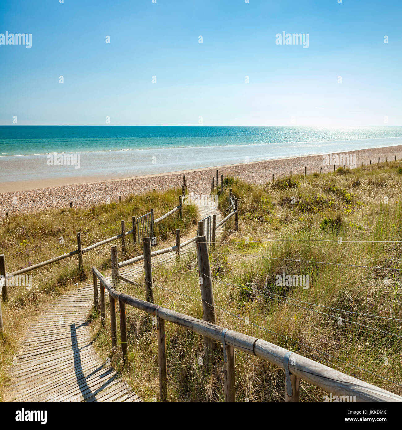 Wooden boardwalk leading into a glistening seascape scene. Stock Photo