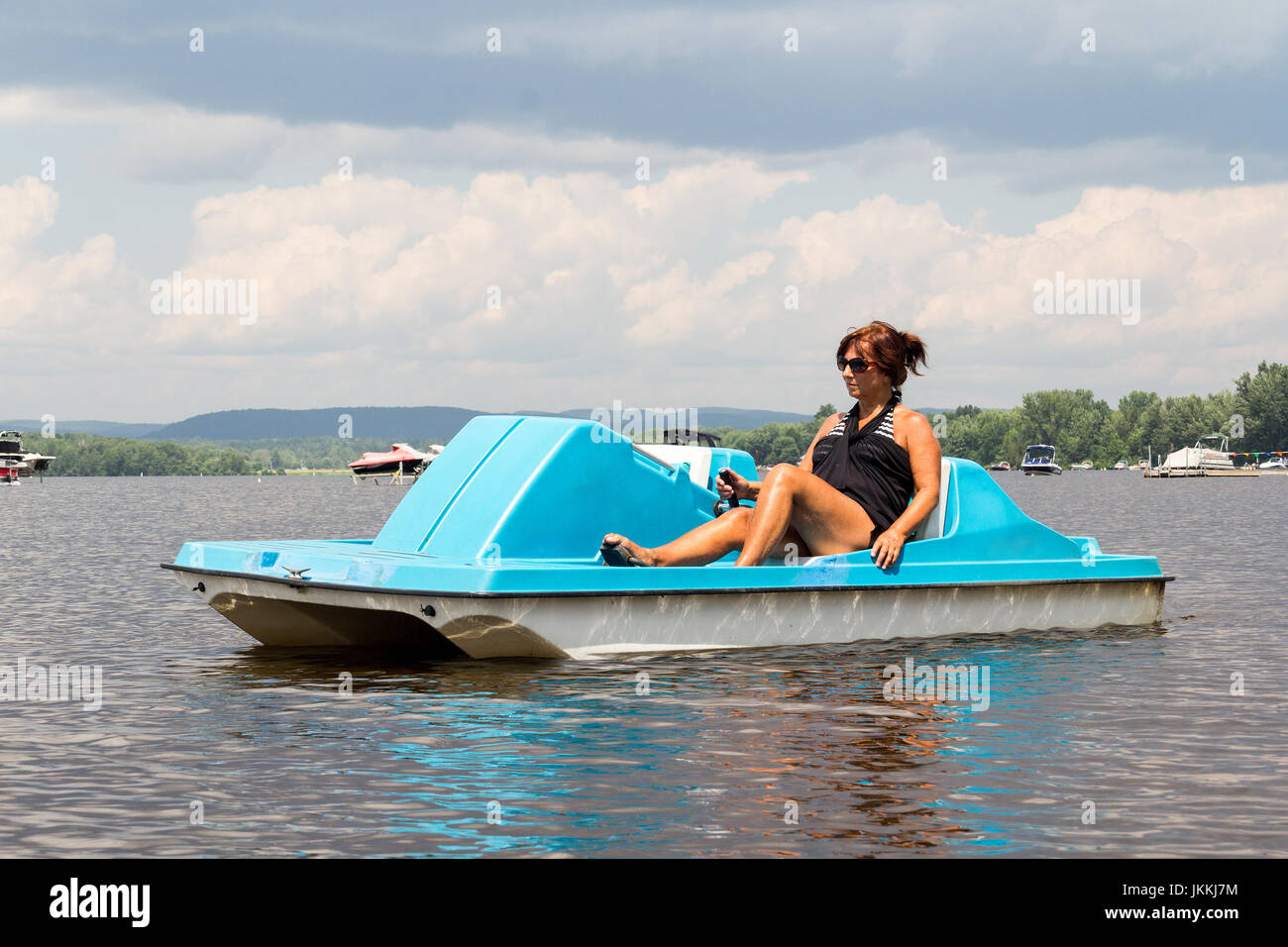 woman on a pedal boat alone on a calm lake at summer Stock Photo