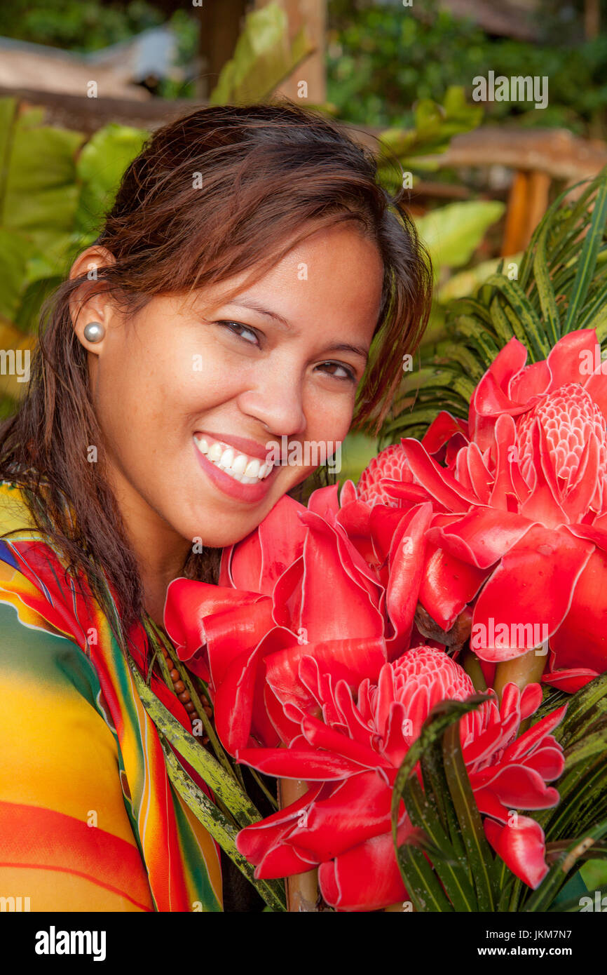 Portrait of a beautiful Filipino woman with a wonderful smile holding a bouquet of red Philippine Wax Flowers, Etlingera elatior. Model released. Stock Photo
