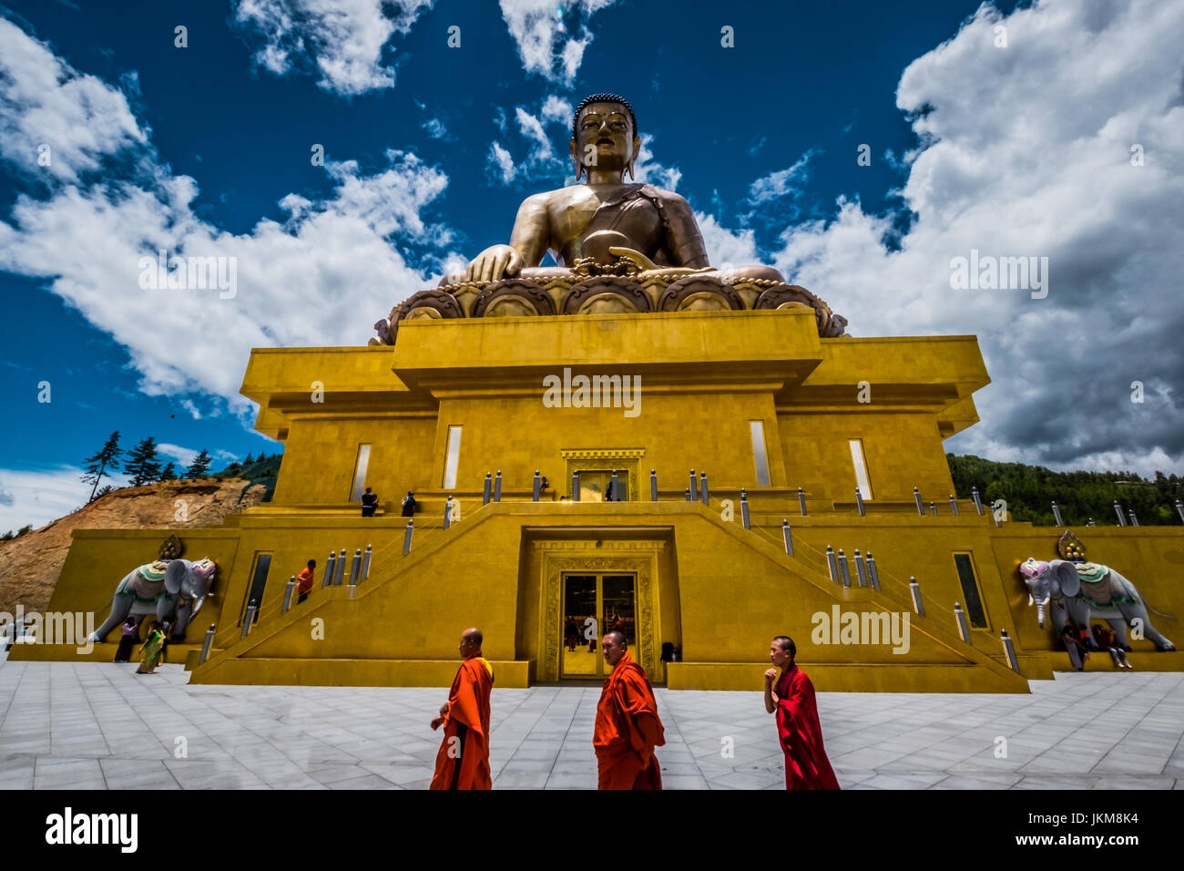 Monks walking by a giant Buddha statue in Bhutan - July 2017 Stock Photo