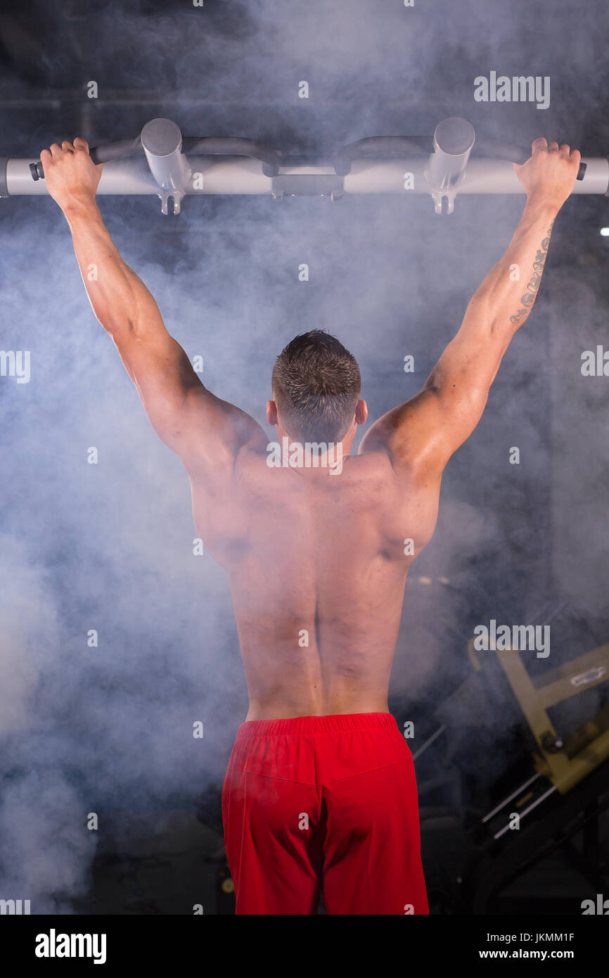 Strong man doing pull-ups on a bar in a gym Stock Photo - Alamy