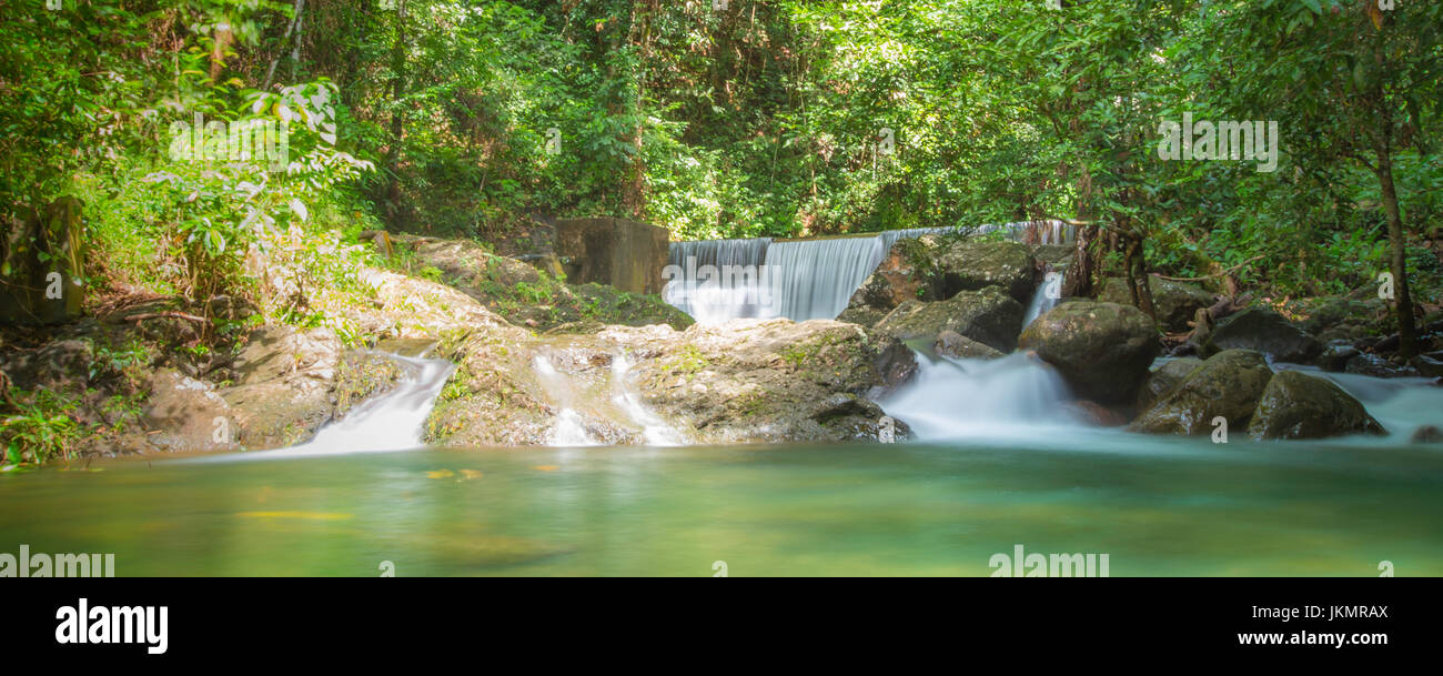Rainforest waterfall pool surrounded by thick green forest trees of tropical plant and species. Ranchan Waterfall, Sarawak, Malaysia Stock Photo