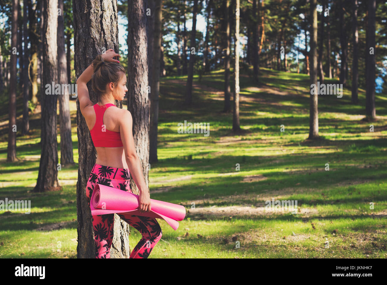 Young fit athletic woman wearing smart watch and holding yoga mat