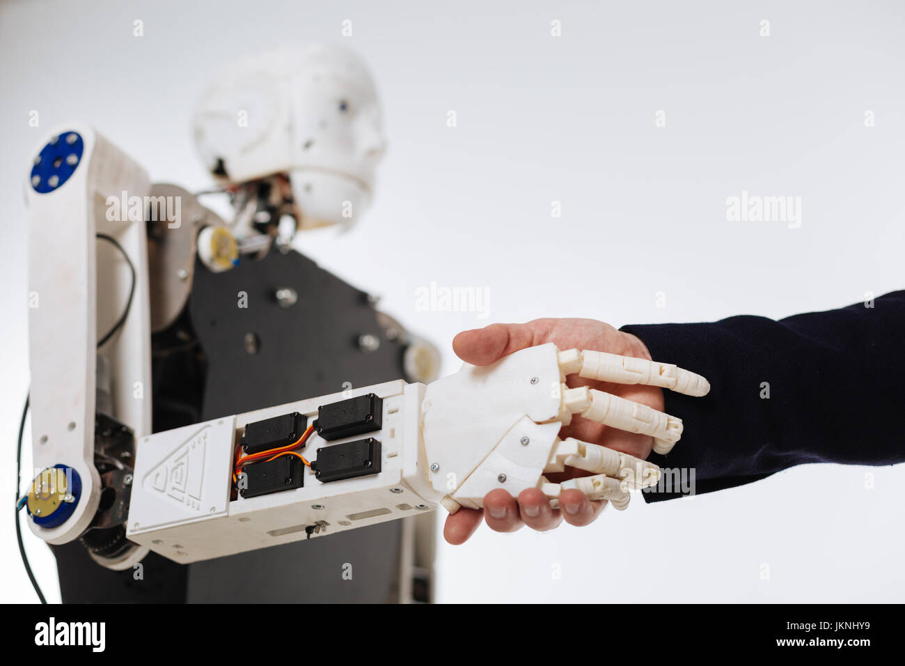 White elaborate robot shaking hands with human Stock Photo