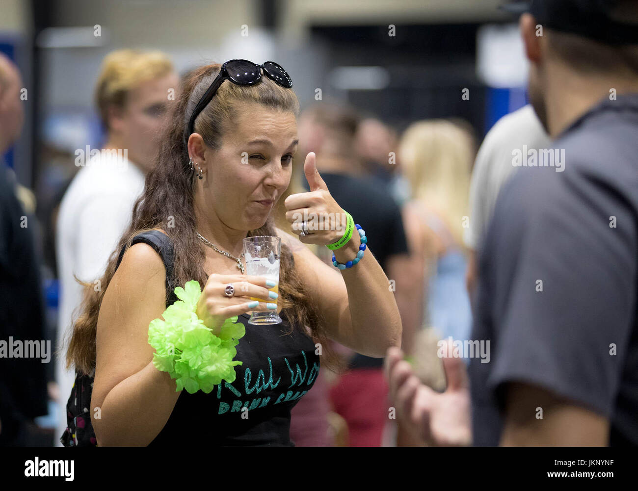 July 22, 2017 - West Palm Beach, Florida, U.S. - Millika Gill, Loxahatchee, gives a thumbs up to her beer sample from Twisted Truck Brewing booth at the Palm Beach Summer Beer Fest at the South Florida Fairgrounds in West Palm Beach, Florida on July 22, 2017. Beer lovers could sample more than 200 craft beers, all in air-conditioned comfort! The beer bash includes the following participating breweries: Twisted Trunk Brewing, Accomplice Brewery and Ciderworks, Ookapow Brewing Company, Devour Brewing Company, Saltwater Brewery, Barrel of Monks Brewing, Bangin' Banjo Brewing Company, Funky Buddha Stock Photo