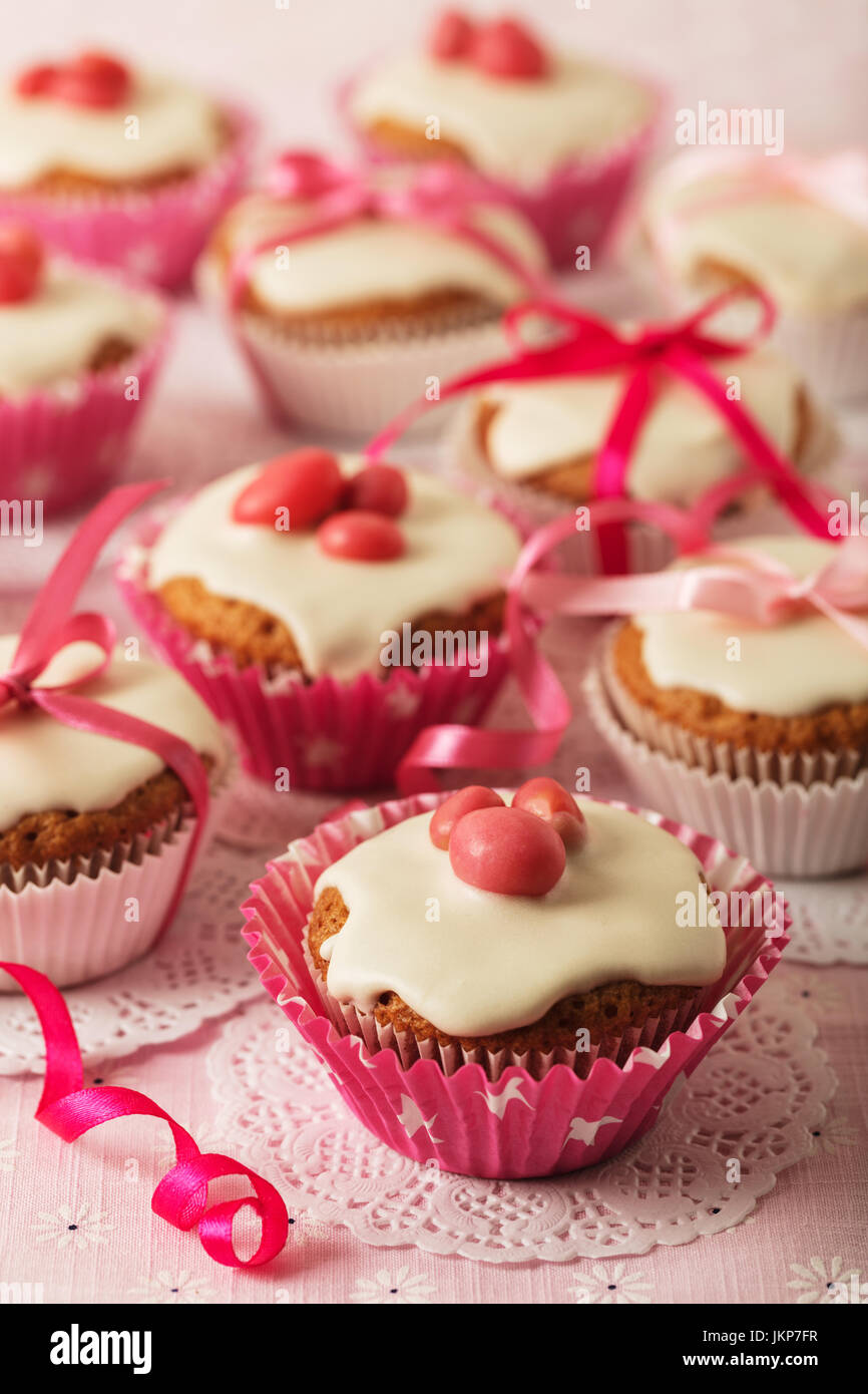 Cupcakes with white icing decorated with pink candy and ribbons. Selective focus. Stock Photo