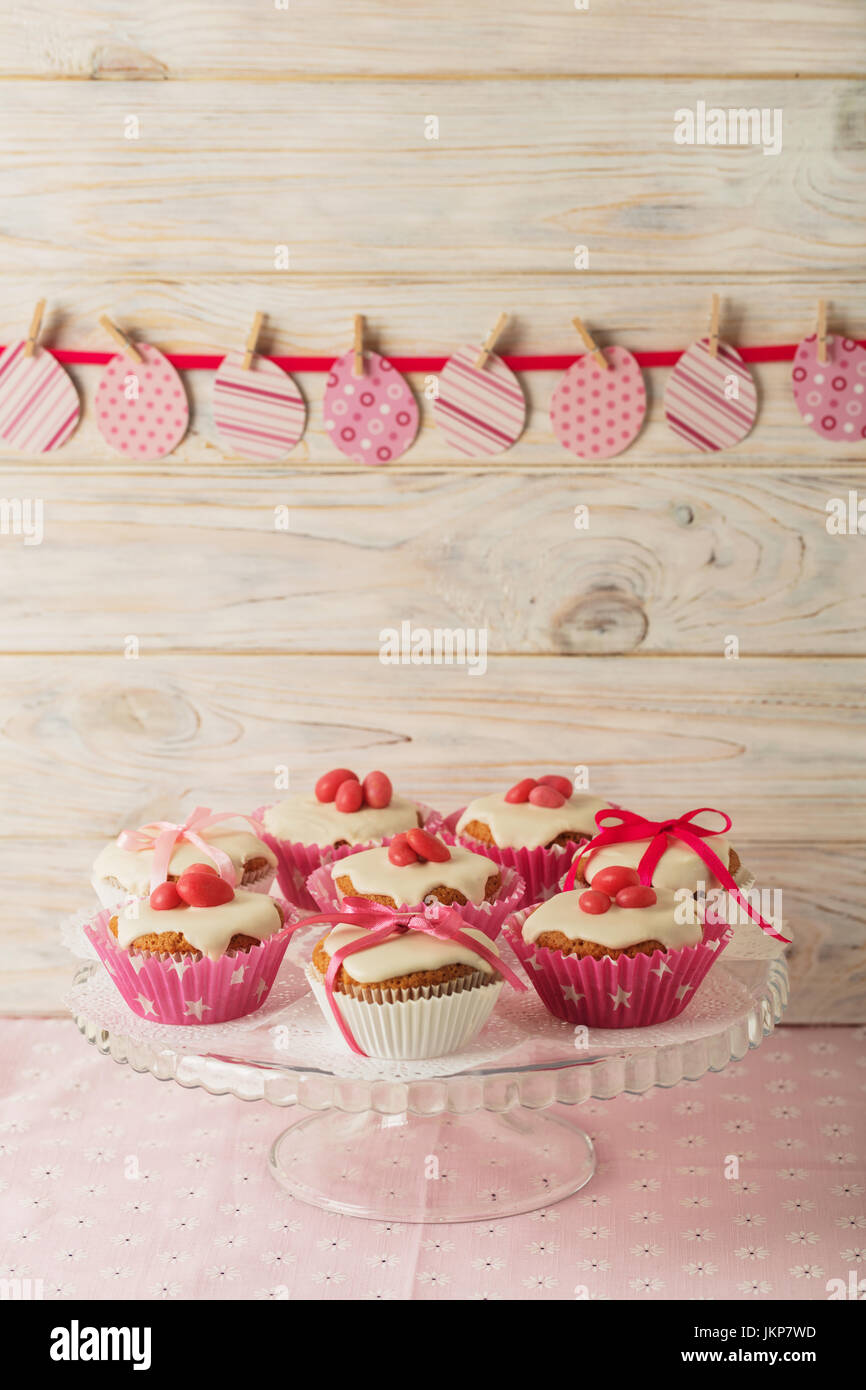 Easter cupcakes with white icing decorated with pink candy and ribbons. Selective focus. Stock Photo