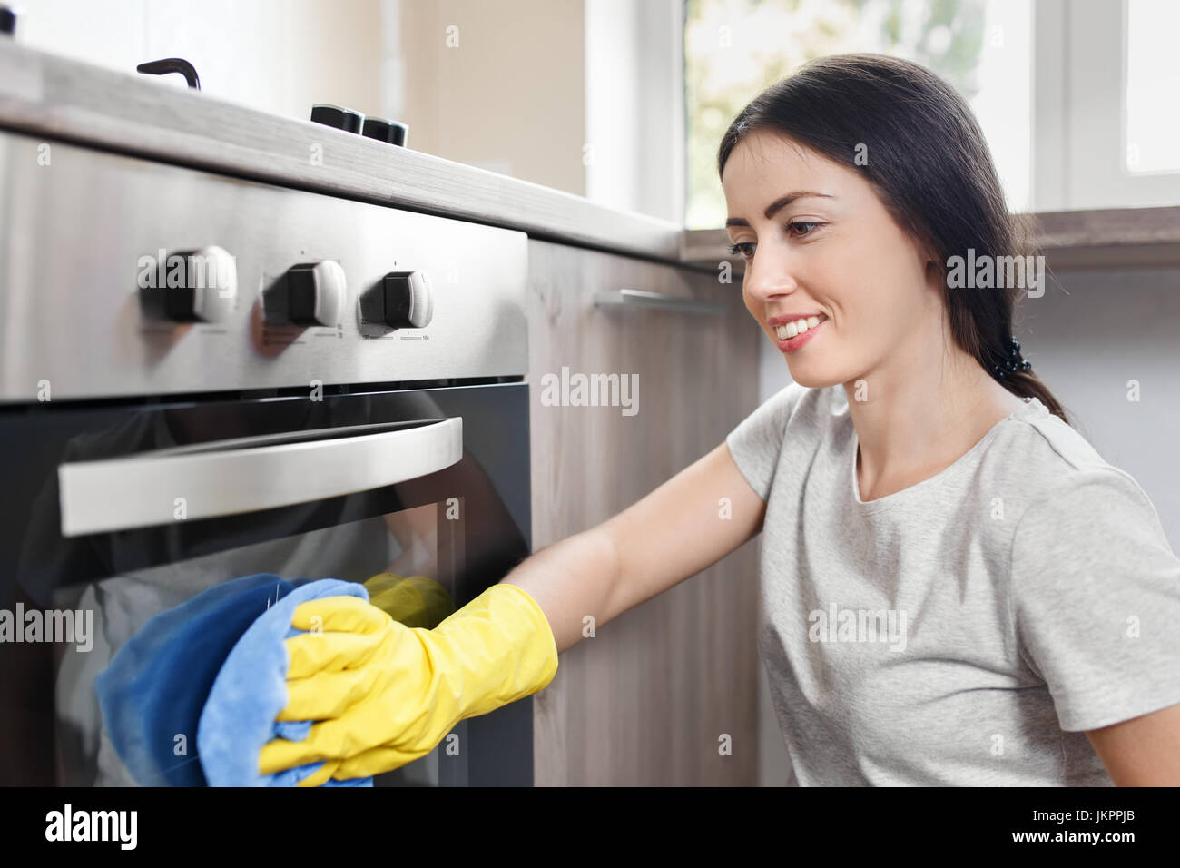 happy woman cleaning oven Stock Photo
