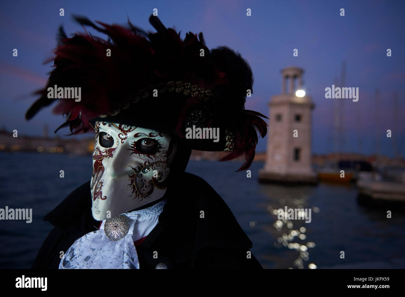 Celebrating Carnival in Venice 2017 in a Bauta mask with a hat garnished with red feathers. Stock Photo